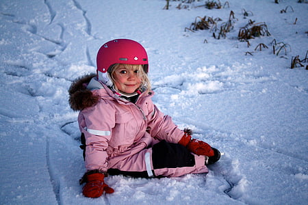 smiling girl sitting on snow during daytime thumbnail