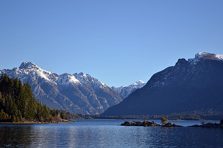 snow-covered mountain beside lake under clear blue sky during daytime thumbnail
