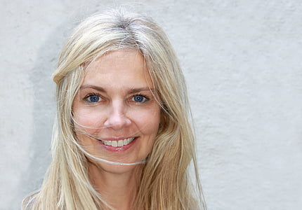 female smiling near white concrete wall thumbnail