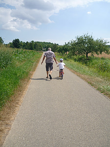 man and kid in bicycle in middle of road thumbnail