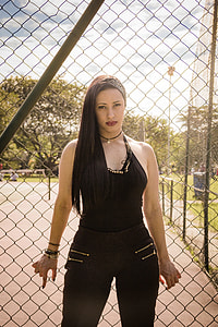 woman leaning on gray wirelink fence during daytime thumbnail