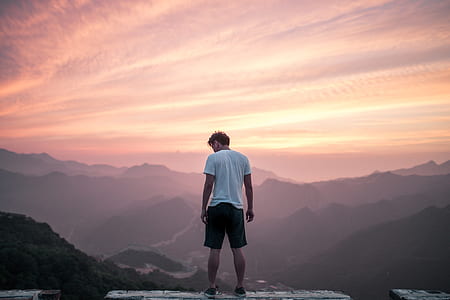 man standing in front of mountain during daytime thumbnail