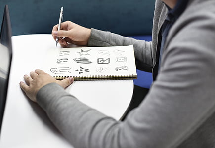 person illustrating in spiral notebook thumbnail