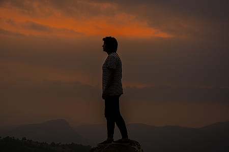 person wearing white and black striped shirt standing on cliff thumbnail