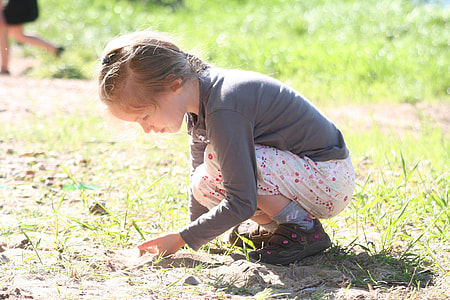 girl in gray long-sleeved shirt crouching on grass field during daytime thumbnail