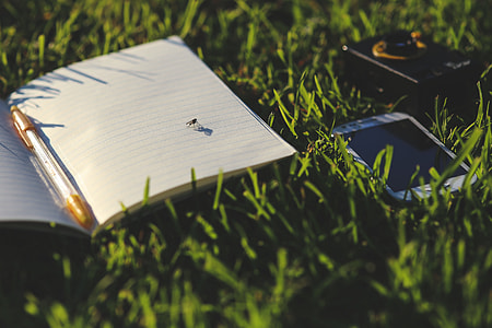 white smartphone beside white notebook on grass thumbnail