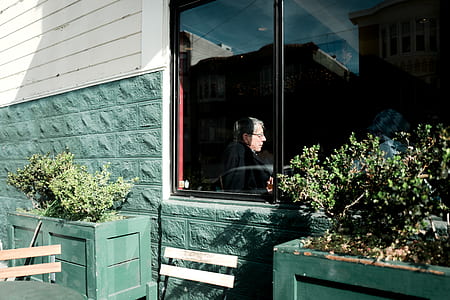 man sitting inside building besides clear glass window thumbnail