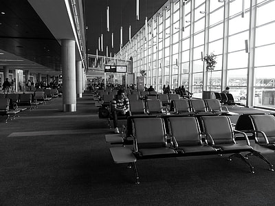 grayscale photography of man sitting inside airport thumbnail