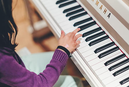 girl playing black and white Yamaha upright piano thumbnail