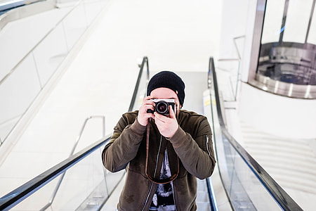 man holding SLR camera on escalator thumbnail