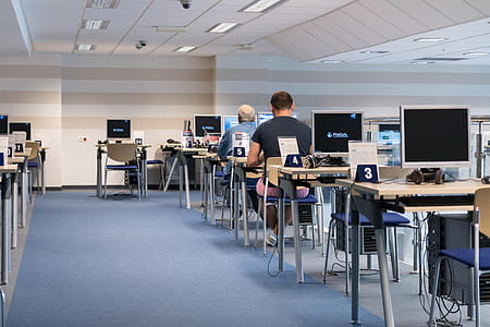 two men sitting on chairs in front of turned on computer monitors thumbnail