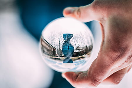 Person Holding Sphere Reflecting Dna-shaped Statue thumbnail