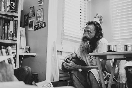 greyscale photography of man sitting on chair near table thumbnail