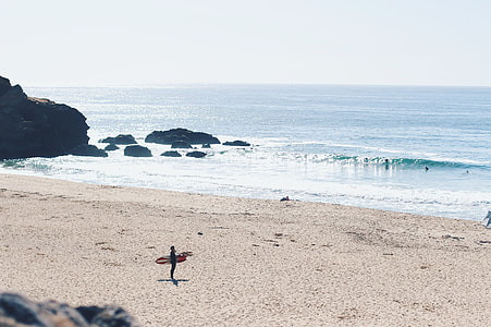 person holding surfboard in seashore during daytime thumbnail