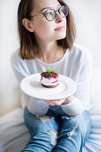 selective focus photography of woman holding plate of cake thumbnail