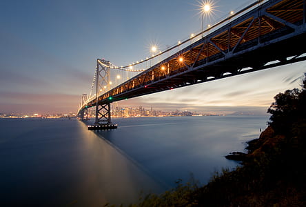 black steel bridge over body of water during sunset thumbnail