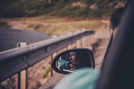 woman wears green jacket inside car seen on vehicle left mirror thumbnail