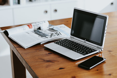 Silver laptop with various items on a table thumbnail