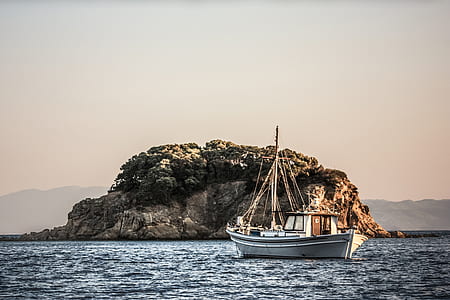 white sailing boat near islet thumbnail