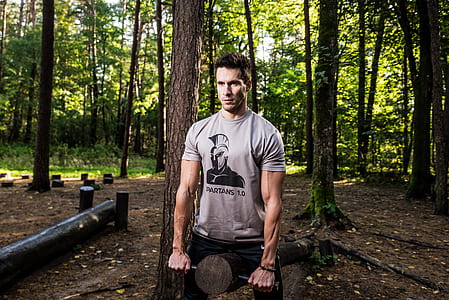 man standing near brown tree carrying brown tree log thumbnail