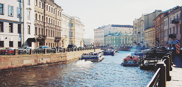 ferries maneuvering on canal between buildings during daytime thumbnail