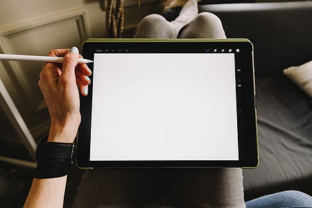 person holding a stylus pen beside black tablet computer thumbnail