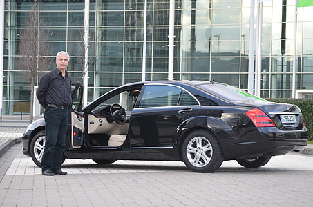 man standing beside black sedan thumbnail