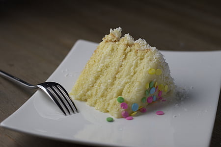 triangular sliced 4-layered cake beside gray stainless steel fork on square white ceramic plate thumbnail