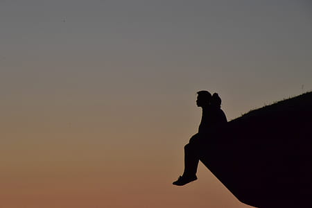 silhouette of person sitting on cliff thumbnail