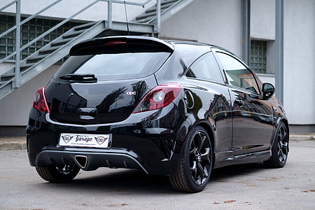 black 5-door hatchback parked near white building thumbnail