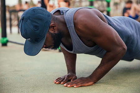A young African man wearing a cap doing push-up exercise outdoors thumbnail