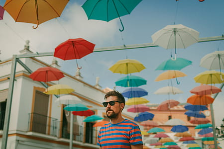 shallow focus photo of man standing near umbrellas thumbnail
