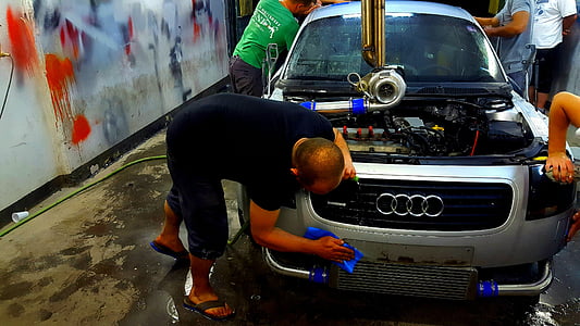 four men doing automotive work on silver Audi inside workshop thumbnail