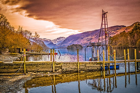 Brown Wooden Bridge Near Mountains and Body of Water thumbnail