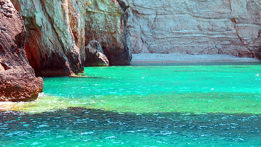 green-tinted clear body of water near brown cliffs thumbnail