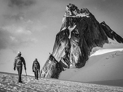 two people walking on snow toward snow capped mountain thumbnail