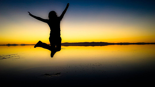 silhouette photo of person jumping near body of water thumbnail