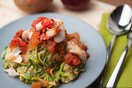 pasta on gray plate beside spoon and fork on white surface thumbnail