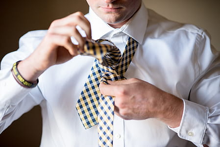 Man Fixing His Necktie in Close-up Photography thumbnail