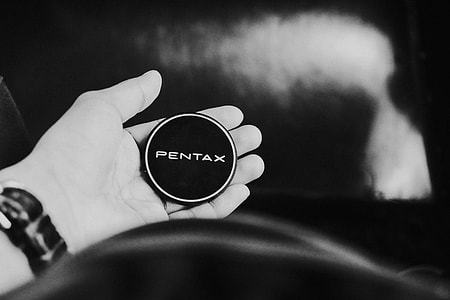 grayscale photo of person holding round Pentax cordless device thumbnail