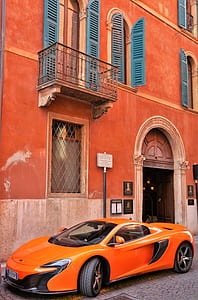 orange McLaren 650S parked on front of concrete building thumbnail