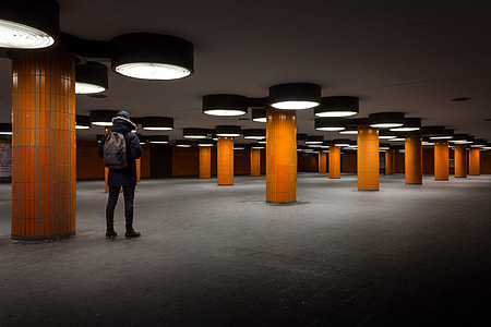 person standing near brown post wearing black jeans carrying backpack thumbnail