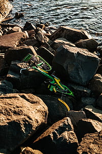 green city bike on rack near body of water thumbnail