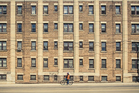 photography of man riding bicycle facing building thumbnail