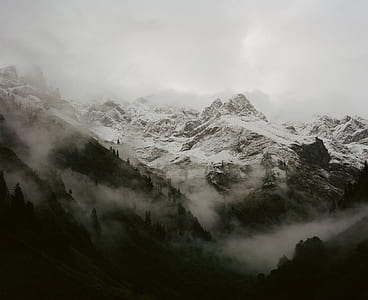 snow capped mountains surrounded by fog thumbnail