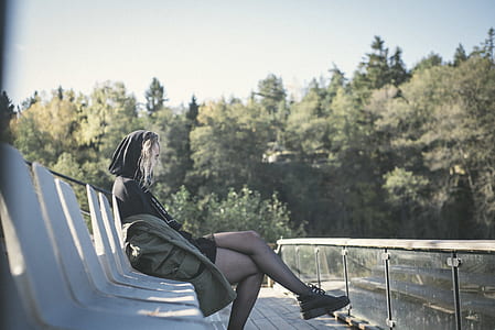 woman sitting on bench under sunny sky thumbnail