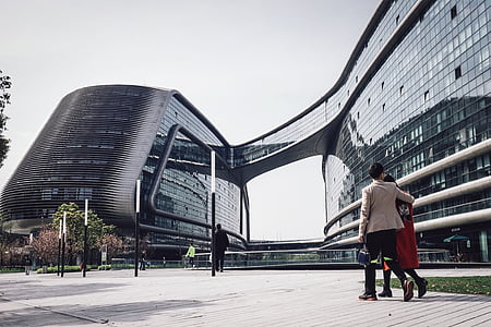 two person walking beside the glass building during daytime thumbnail