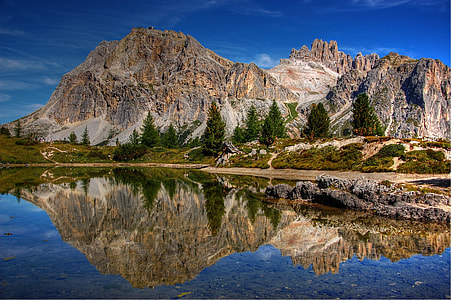 view of gray and brown mountain with reflection on blue water body thumbnail