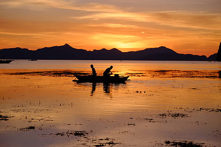 silhouette of two persons in boat under sunset thumbnail