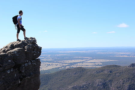 man with black backpack standing on mountain thumbnail